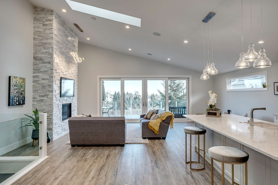A stunning living room and kitchen area with large windows, two sofas and lots of natural light.